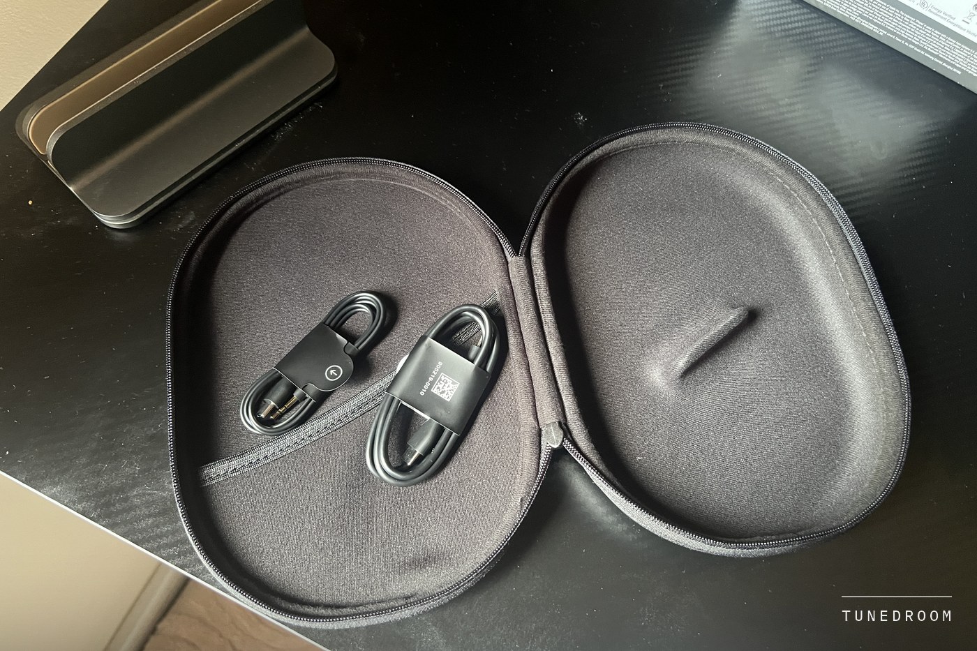 The open hardshell case with the USB-C to USB-C and USB-C to 3.5 mm cables stowed inside