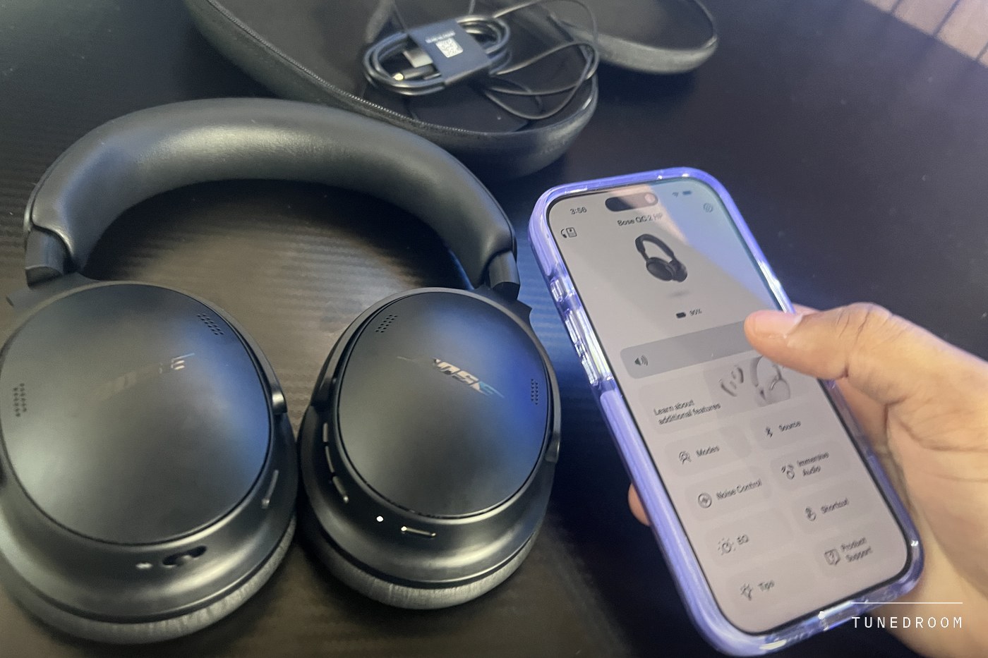 A phone running the Bose app beside the headphones, showing the listening mode controls