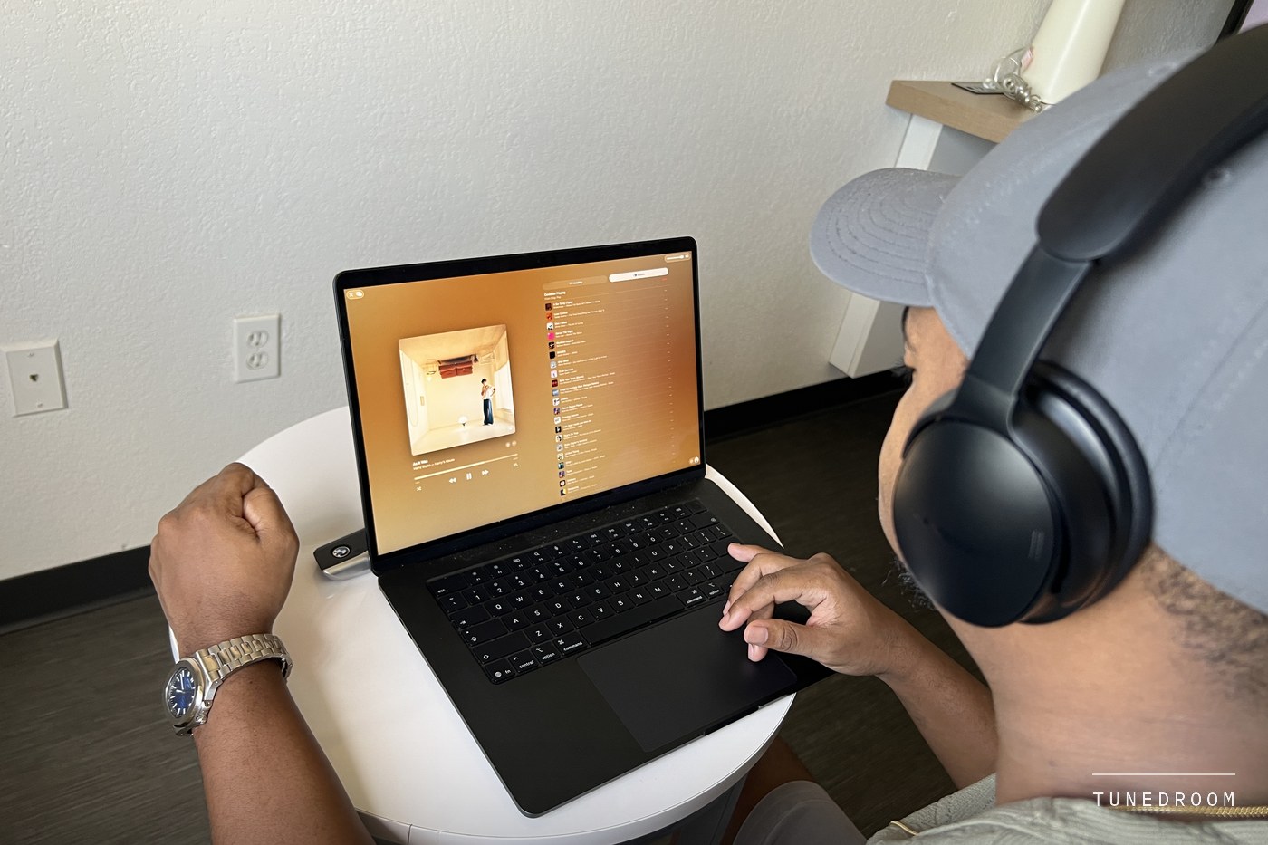 The headphones worn at a small table while watching something on a laptop