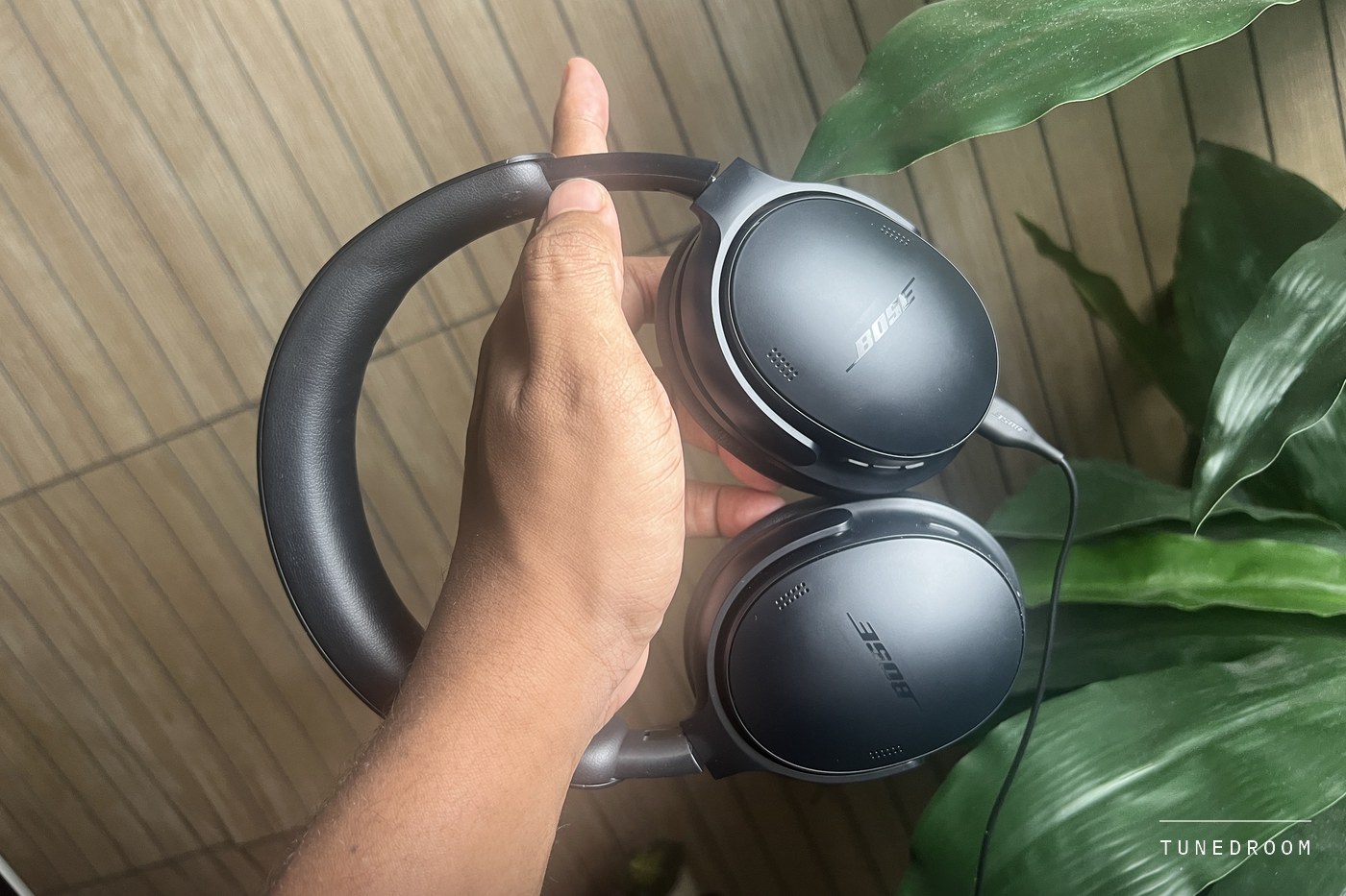 The headphones held by the headband with the USB-C cable hanging from one earcup
