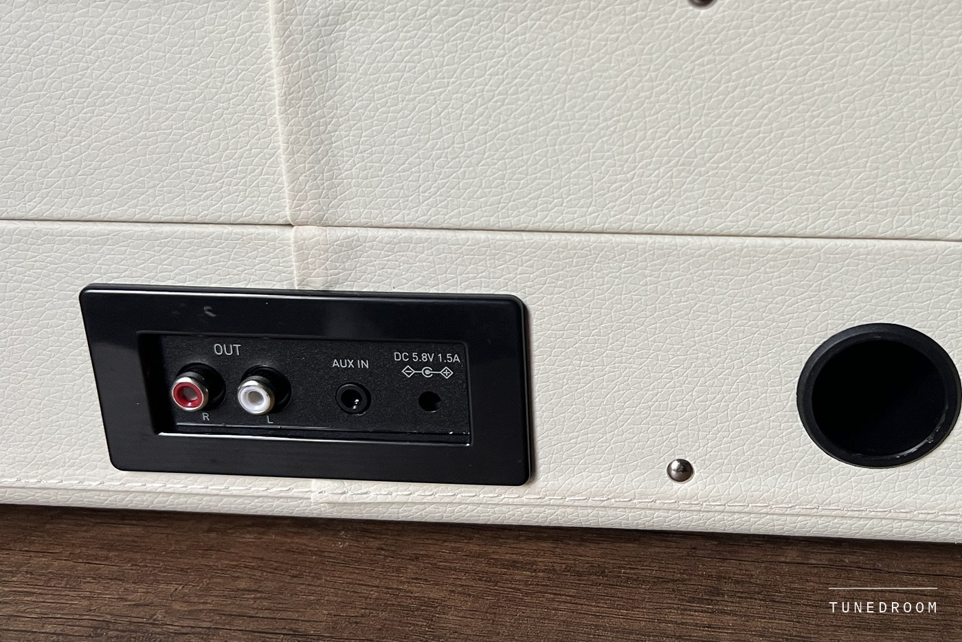 The rear jack panel on the Revival 65's cream case: red and white RCA OUT jacks, a 3.5 mm AUX IN socket and the DC power socket, with a round opening and a case latch beside it