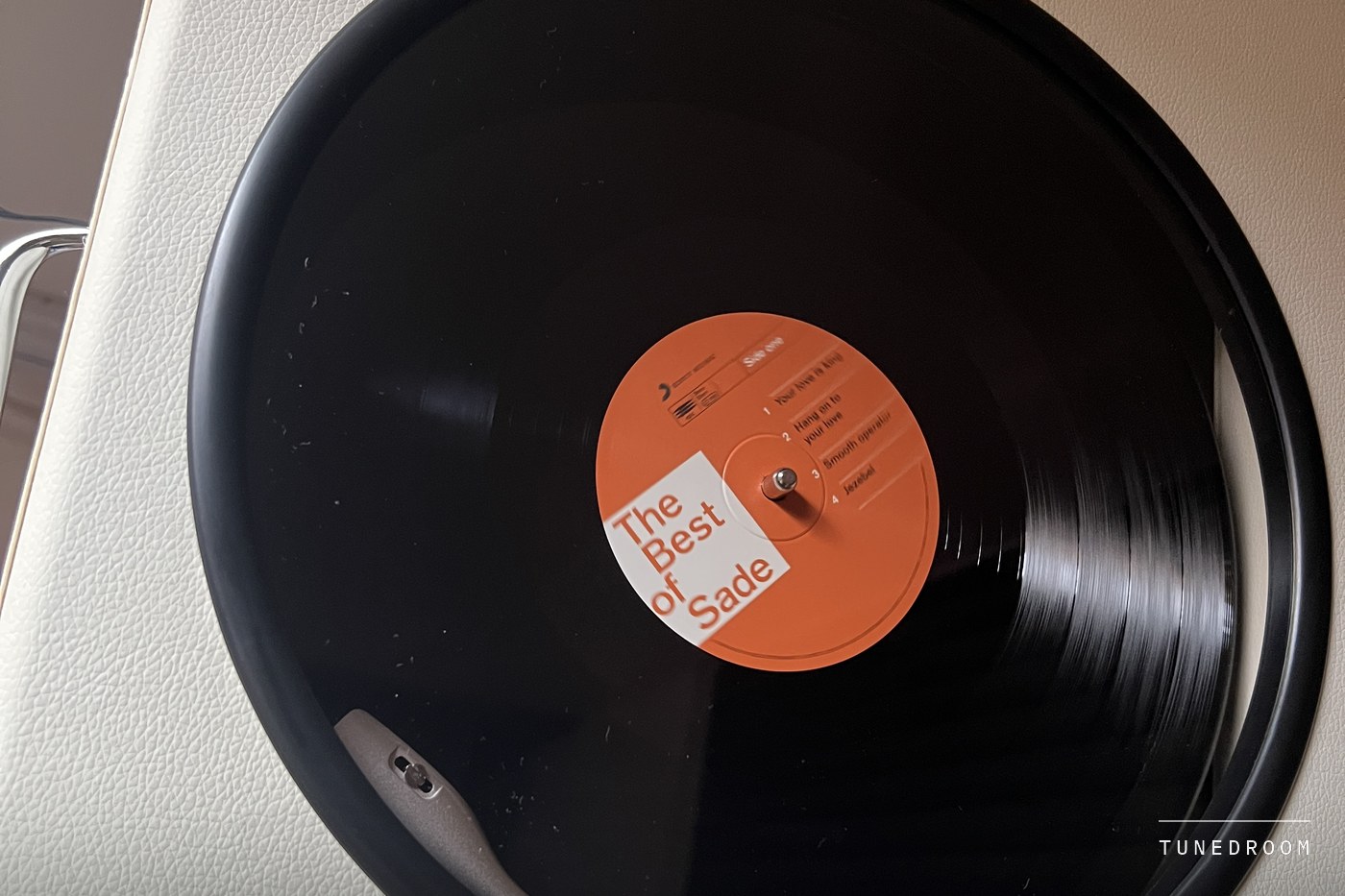 A copy of The Best of Sade turning under the Revival 65's closed lid, seen through the round glass window
