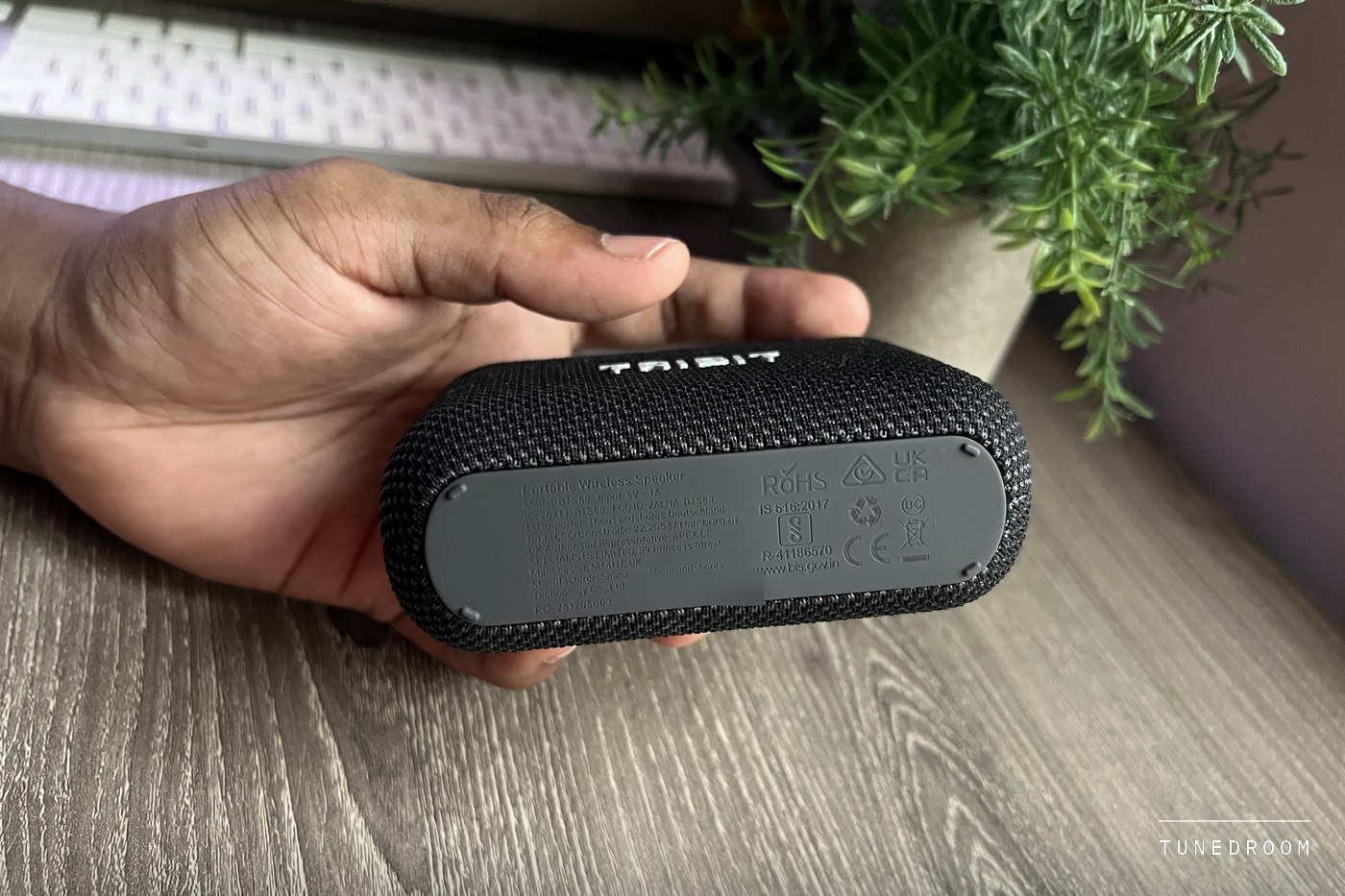 The PocketGo held in a palm with its underside toward the camera, showing the grey base panel with its model and certification markings