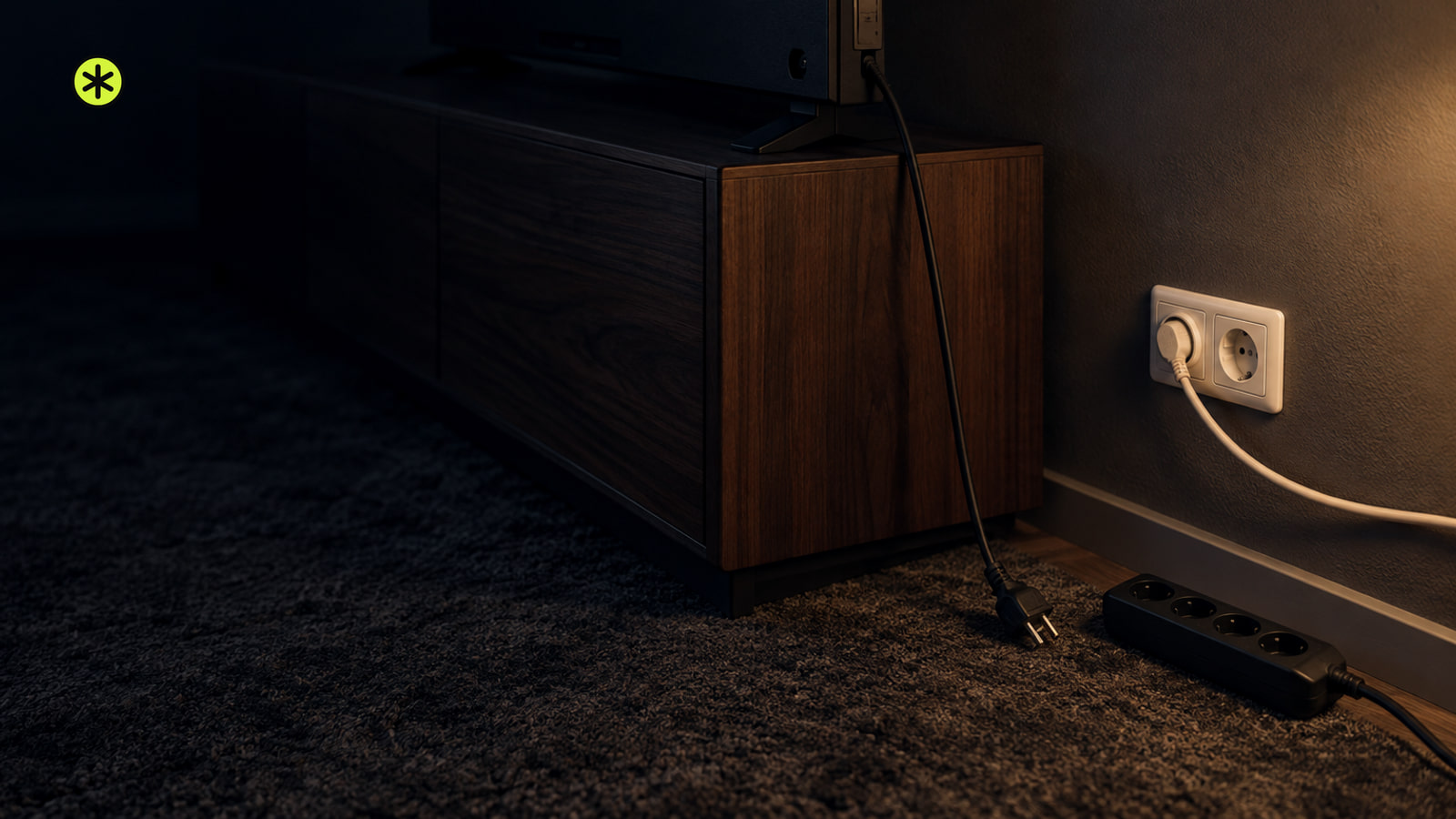 Dark TV corner on a walnut console, its unplugged power cord and a power strip lying on a rug by a white wall outlet, lit low by a warm lamp.