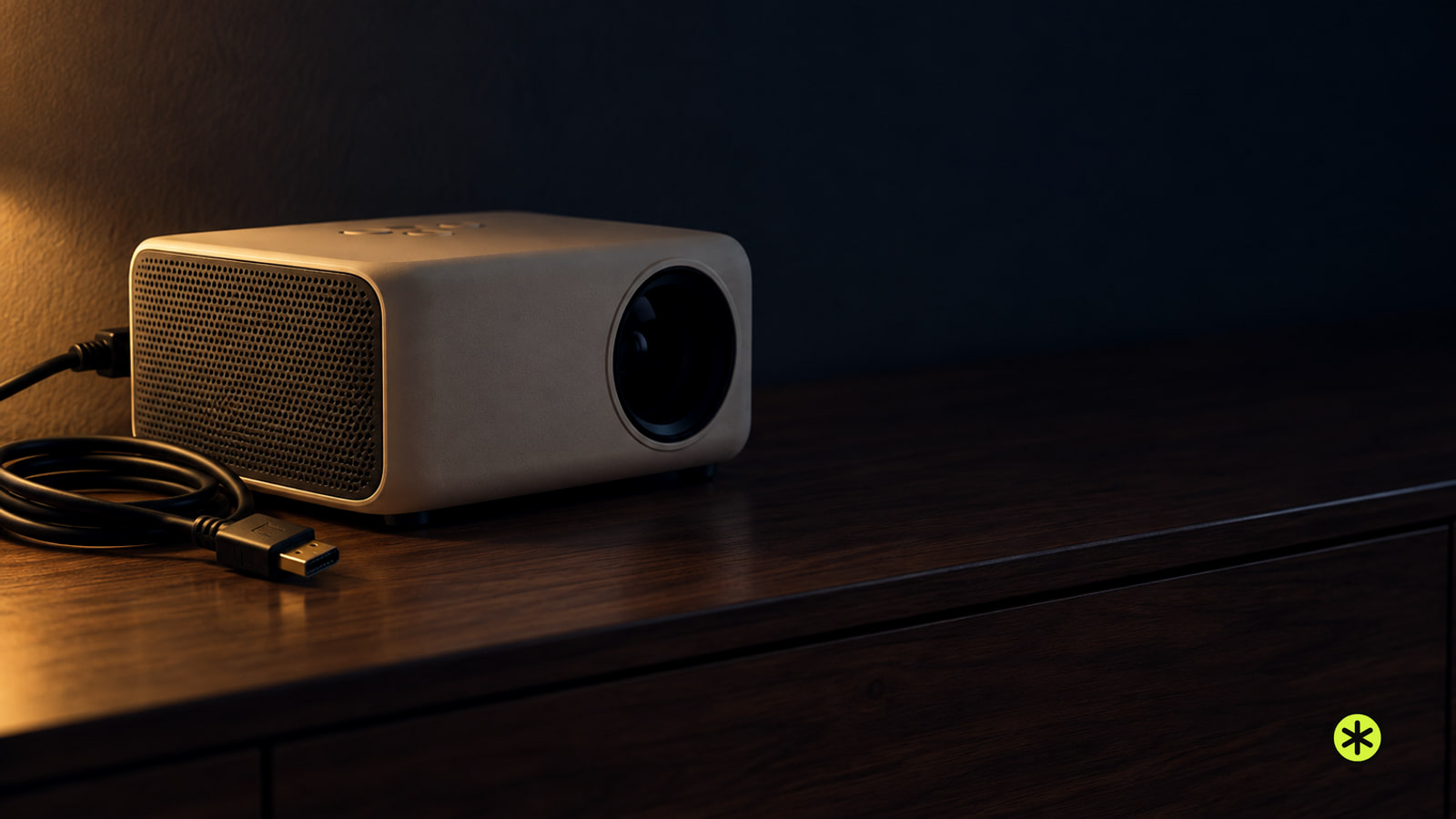 Cream projector with a dark lens and speaker grille on a walnut console at night, a spare black HDMI cable coiled beside it, lit by a low warm lamp.