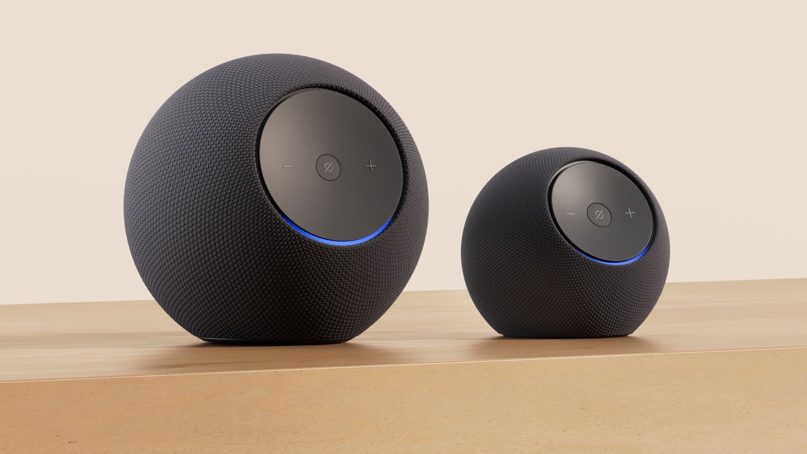 Two dark fabric-covered Echo speakers of different sizes have circular controls and blue light rings.